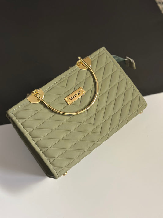 A light sage green quilted leather handbag with a gold-tone metal ring handle and a small gold brand plaque reading 'LEAVIER'.