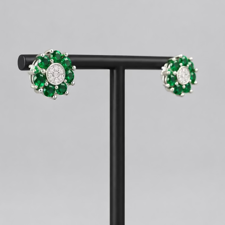A pair of floral cluster stud earrings with green gemstones and a central clear stone, displayed on a black T-stand against a light gray background.