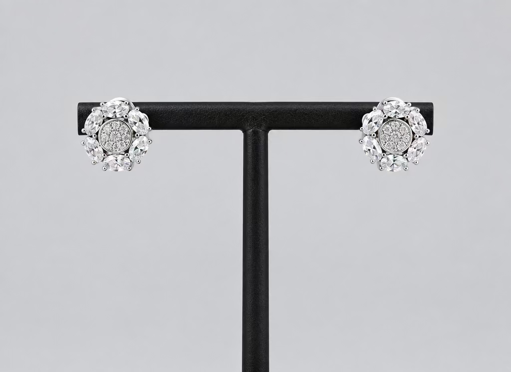 A pair of silver-toned cluster stud earrings with clear gemstones, displayed on a black T-stand against a light gray background.