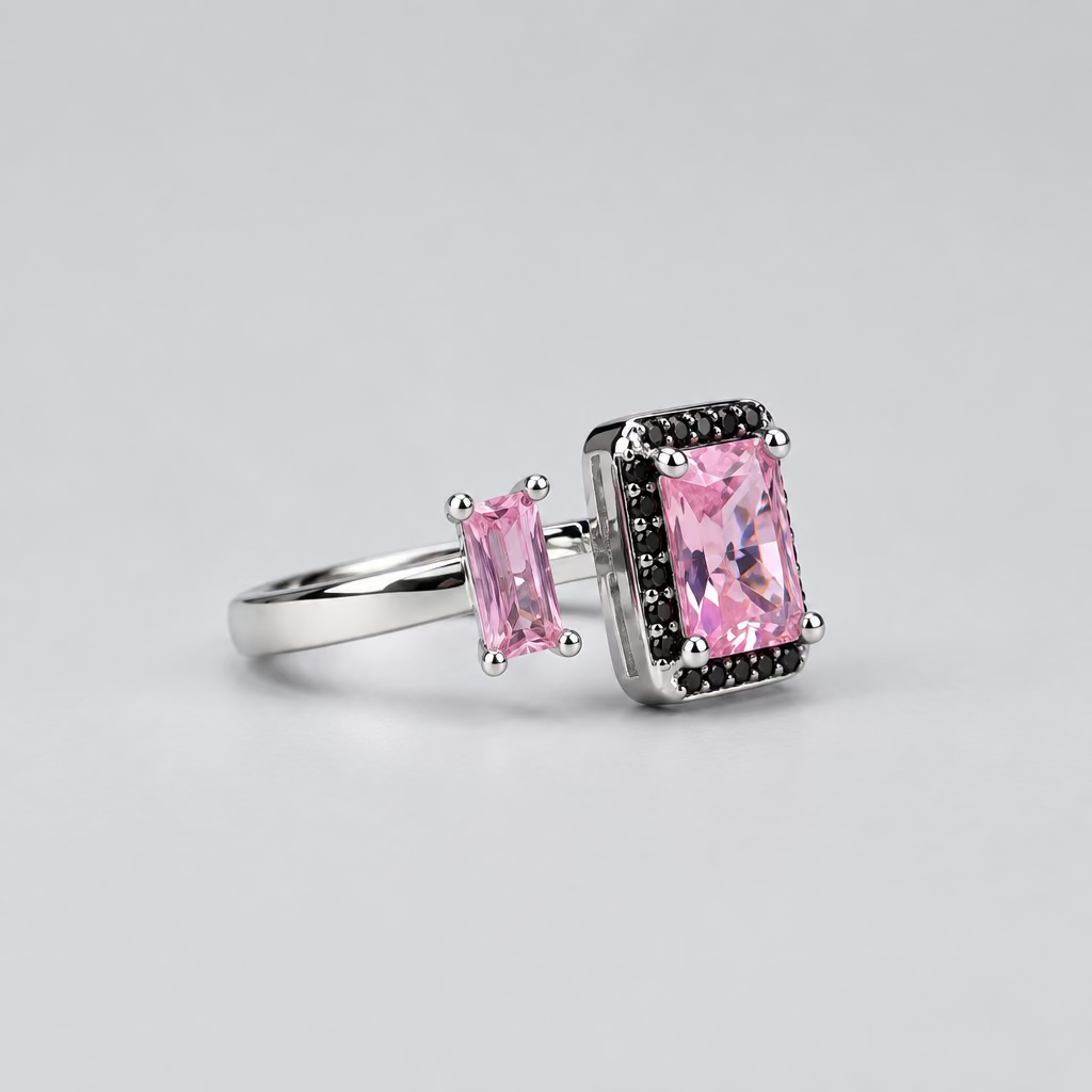 A silver ring with a rectangular pink gemstone and two smaller pink stones, displayed in front of a white jewelry box with the Meenu Jewels logo on a dark gray background.