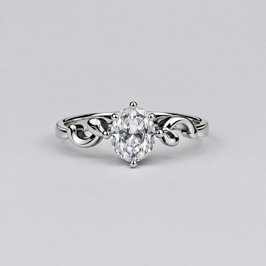 A silver ring with a heart-shaped clear gemstone is displayed in the foreground on a light surface, with a white jewelry box branded 'Meenu' in the blurred background against a dark backdrop.