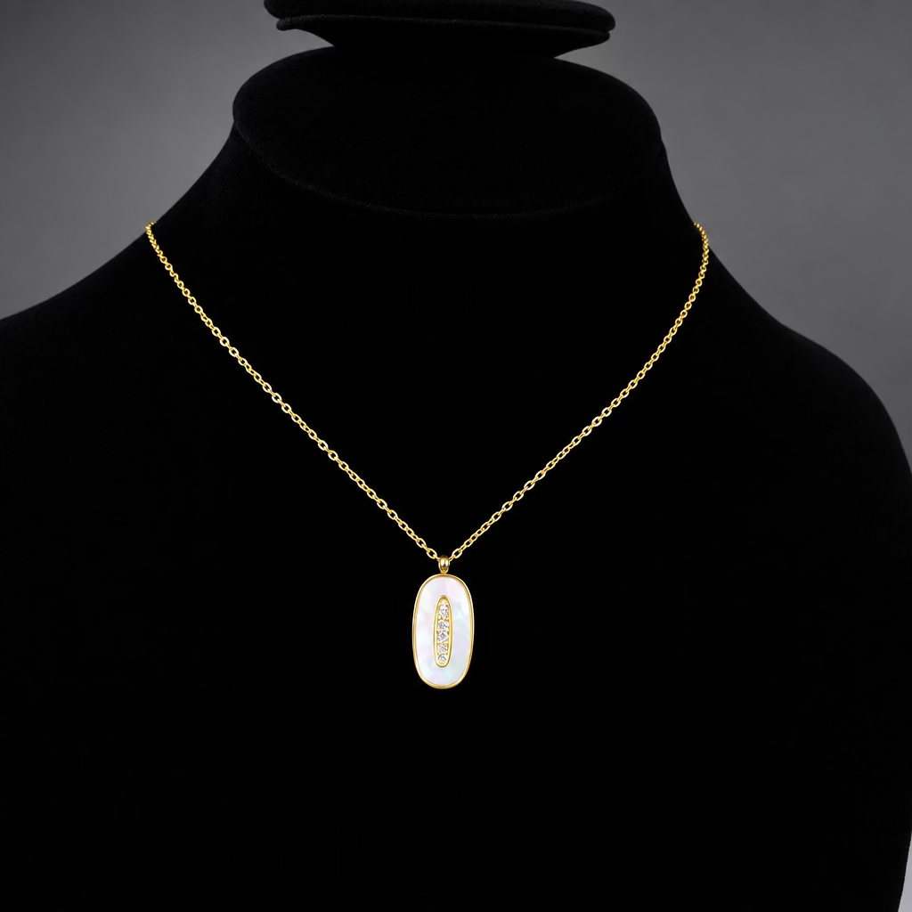 A gold chain necklace with an oval pendant featuring a white iridescent center and a small gold feather motif, displayed on a black velvet jewelry bust.