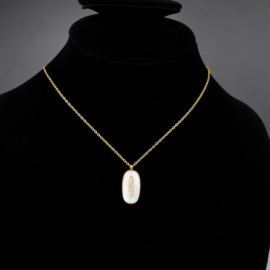A gold chain necklace with an oval pendant featuring a white iridescent center and a small gold feather motif, displayed on a black velvet jewelry bust.