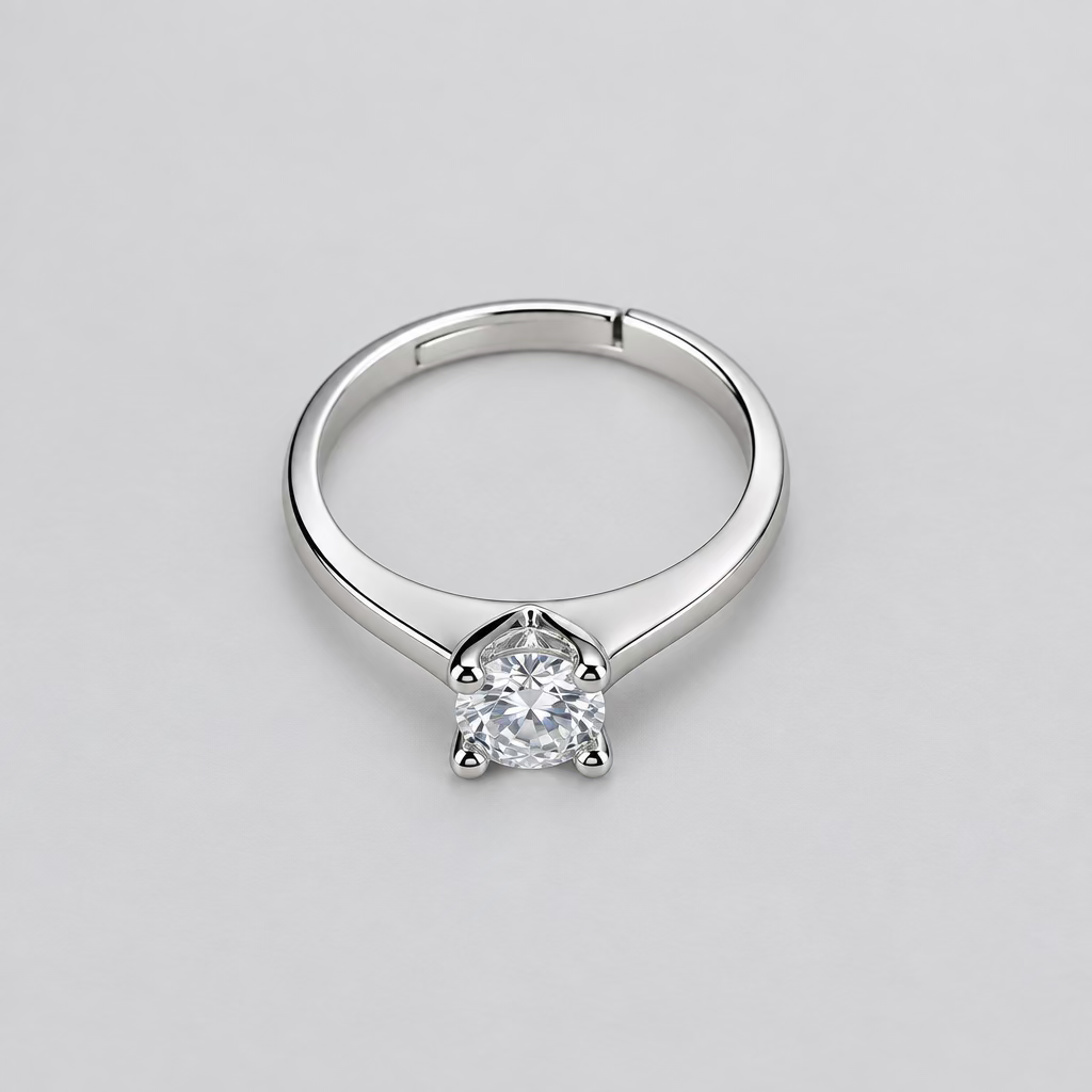 A silver-toned solitaire ring with a clear gemstone, displayed on a textured white fabric background.