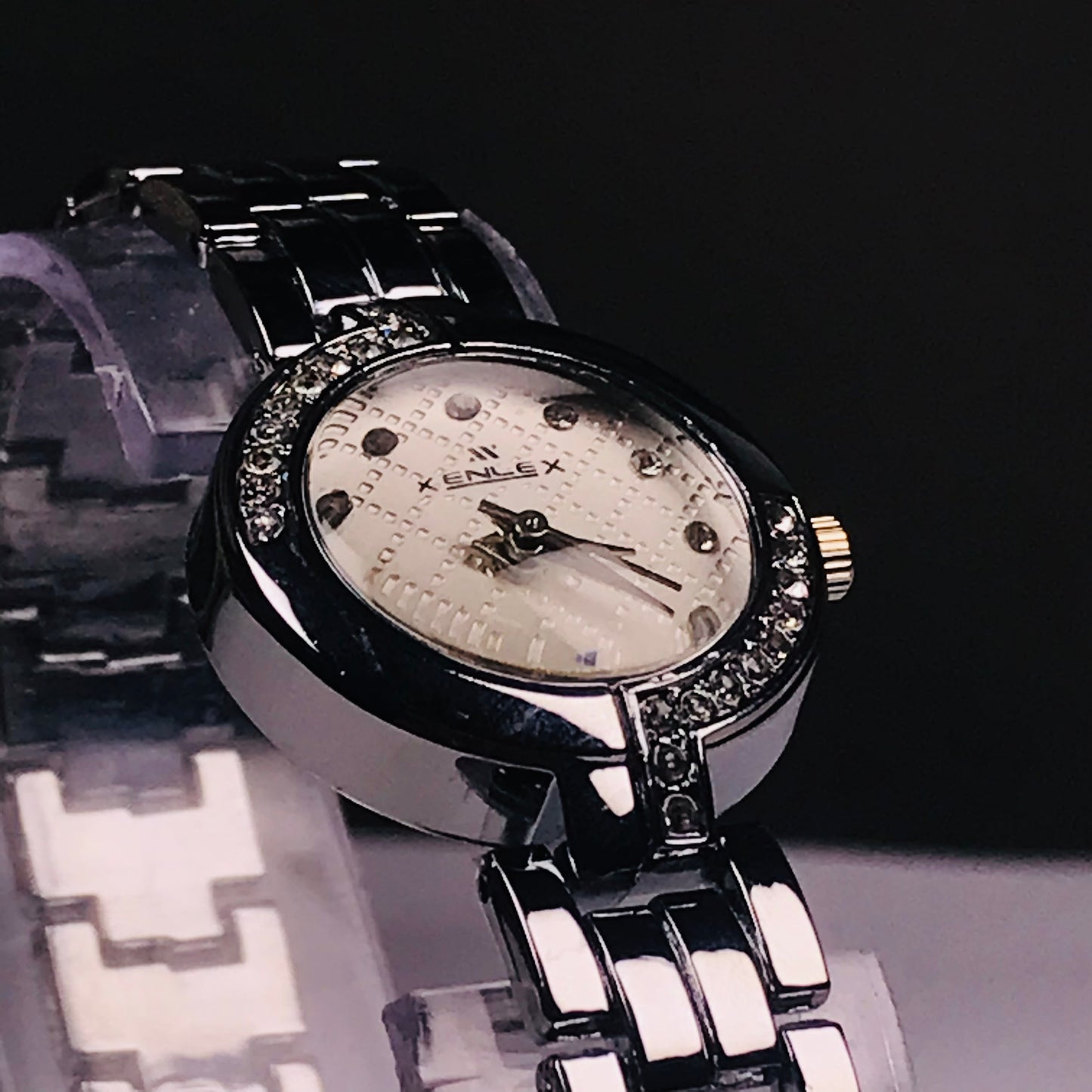 A close-up shot of a Kenlex women's watch featuring a silver-tone metal bracelet, a white textured dial, and a bezel set with small clear crystals.